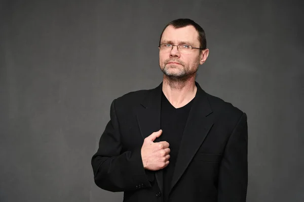 Zakenman met bril kijkt naar de camera. Portret op een grijze achtergrond in de studio — Stockfoto