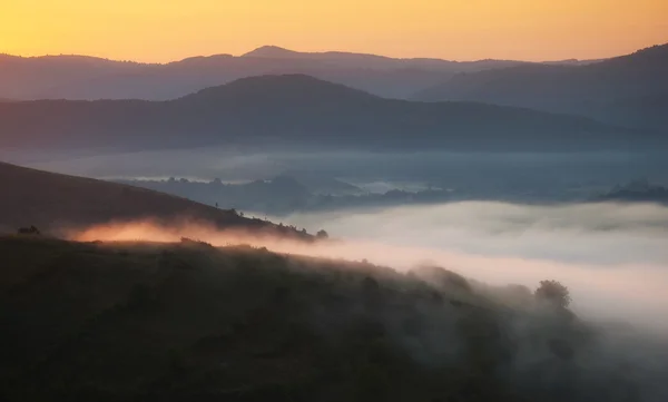 Nebel fließt durch Wiesen und Hügel an einem Herbstmorgen bei Sonnenaufgang mit Sonnenlicht — Stockfoto