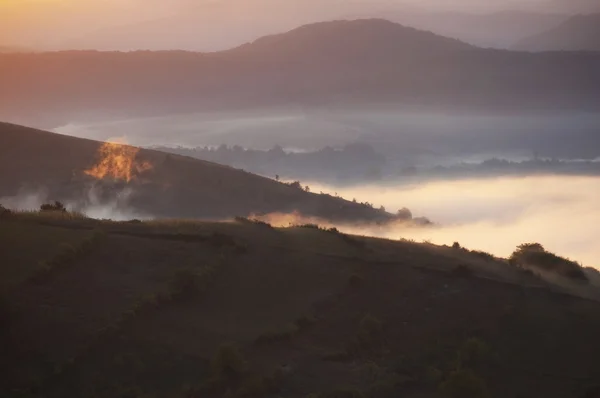 Nebelschwaden durch Hügel am Herbstmorgen bei Sonnenaufgang — Stockfoto