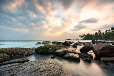 Sri Lanka 'da, Matara yakınlarında palmiyelerin altında görülen kayalar ve deniz üzerinde güzel renkli bir gün batımı.. 
