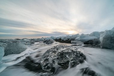 Gün batımında Jokulsarlon sahilinde siyah kumlu buz kayası. Güneydoğu İzlanda 'da elmas plajı.