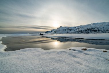 Dağların manzarası ve karla çevrili su birikintisi. İzlanda 'da kış
