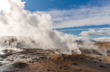 İzlanda 'daki Namafjall Hver jeotermal alanı. Duman tüten fümerolleri ve mavi bulutlu gökyüzü, seyahat geçmişi, turistik cazibesi olan şaşırtıcı kükürt vadisi manzarası.
