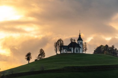 Bulutlu havada renkli bir gün batımı. Kilisenin manzarası Sv Sobota. Slovenya sonbaharda