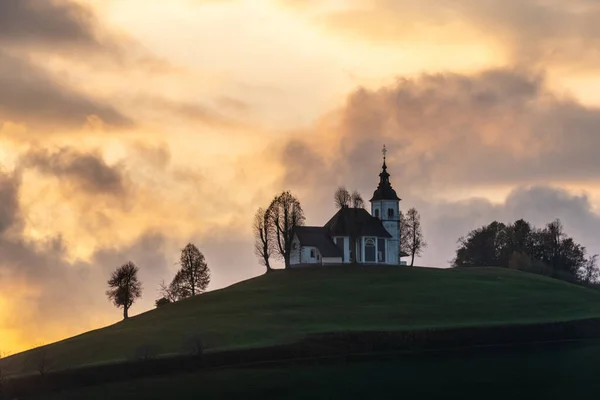Ein farbenfroher Sonnenuntergang bei bewölktem Wetter. Blick auf die Kirche Sv Sobota. Slowenien im Herbst lizenzfreie Stockbilder