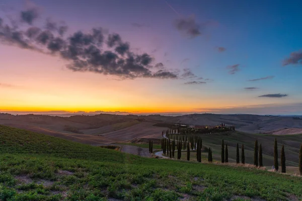 Tuscany, rural landscape at sunset. Rural farm, cypresses, green field, sunshine and clouds. Italy, Europe. — Stock Photo, Image