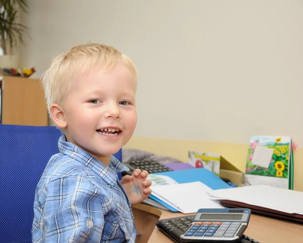Симпатичный мальчик в офисе с калькулятором — стоковое фото