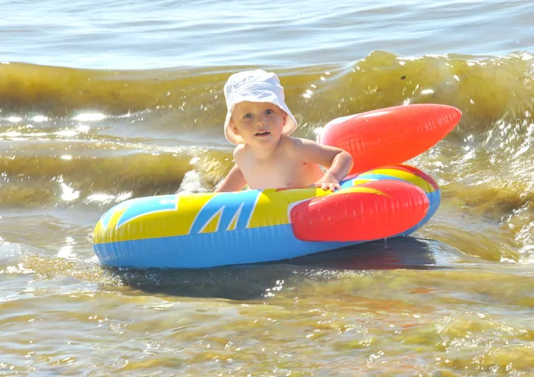Netter Junge, der ein Boot am Strand rudert — Stockfoto