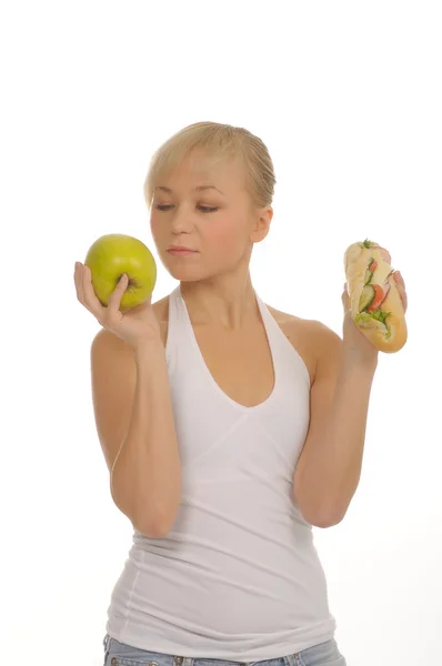 Slim woman choosing between apple and hamburger — Stock Photo, Image