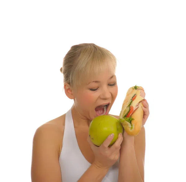 Тонкая женщина выбирает между яблоком и гамбургером — стоковое фото