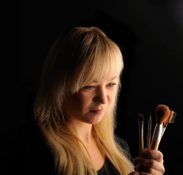 Joven rubia cabello mujer retrato con maquillaje cepillo sobre fondo oscuro — Foto de Stock