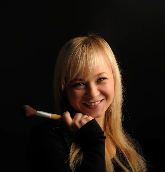 Junge blonde Haare Frauenporträt mit Make-up-Pinsel auf dunklem Hintergrund — Stockfoto