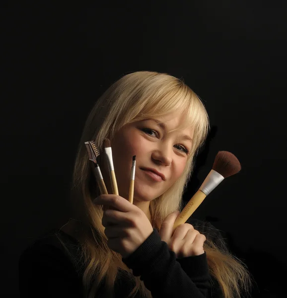 Jeune portrait de femme aux cheveux blonds avec pinceau de maquillage sur fond sombre — Photo