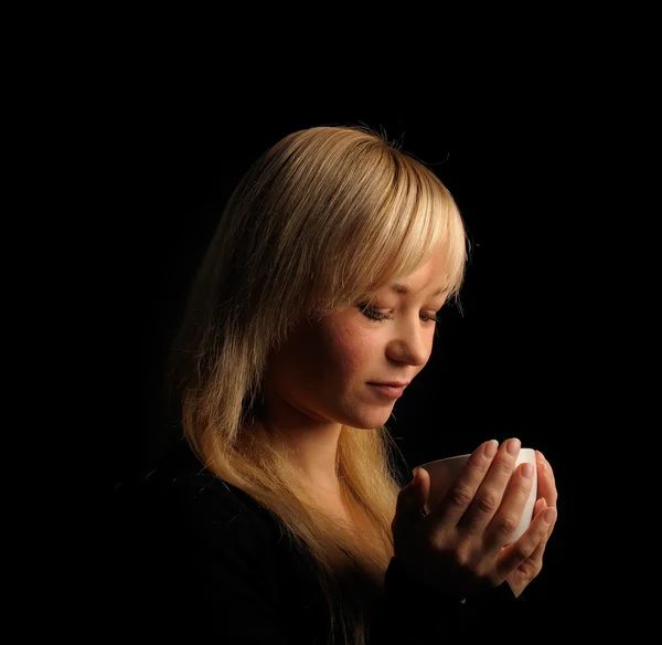 Mladá blond vlasy žena s káva na tmavém pozadí — Stock fotografie