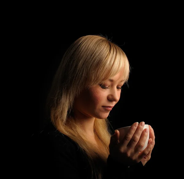 Jeune femme aux cheveux blonds avec café sur un fond sombre — Photo