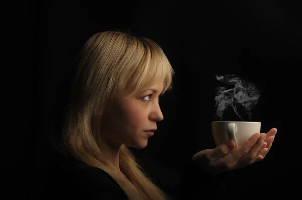 Νεαρό ξανθιά μαλλιά γυναίκα με καφέ σε σκούρο φόντο — Φωτογραφία Αρχείου
