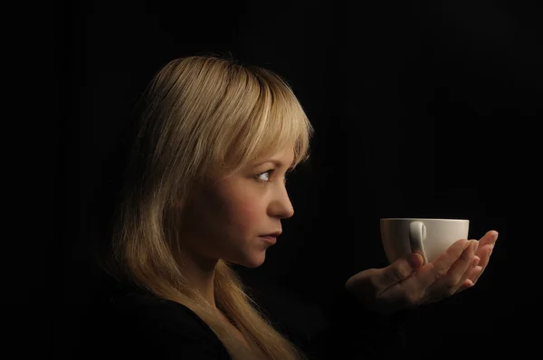 暗い背景にコーヒーと若いブロンドの髪の女性 — ストック写真