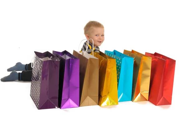 Schattige jongen met shopping tassen na het winkelen. geïsoleerd op wit — Stockfoto