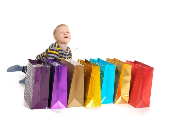 Carino ragazzo con le borse della spesa dopo lo shopping. isolato su bianco — Foto Stock