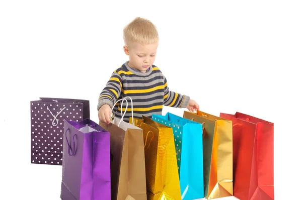 Lindo chico con bolsas de compras después de comprar. aislado en blanco —  Fotos de Stock