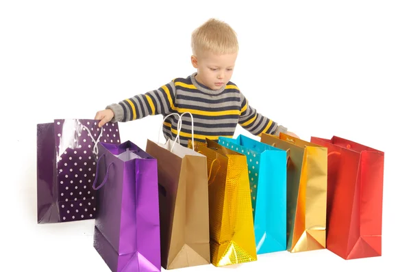 Schattige jongen met shopping tassen na het winkelen. geïsoleerd op wit — Stockfoto