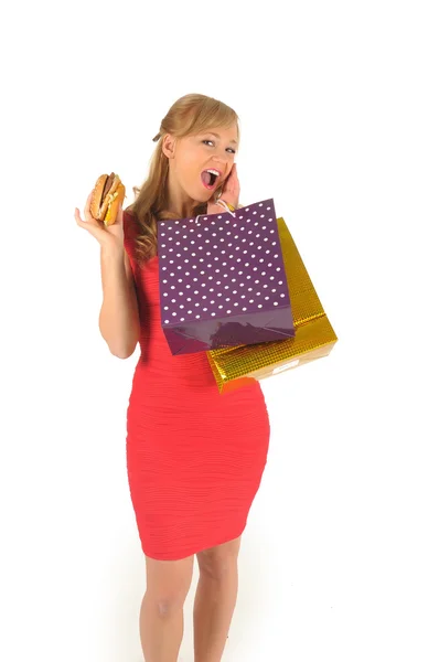 Молодая красивая женщина с сумками и гамбургером изолированы на белом — стоковое фото