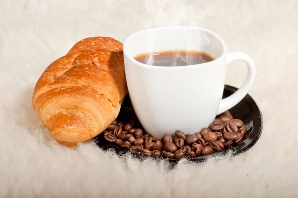 Croissant with coffee and beans on fur background — Stock Photo, Image