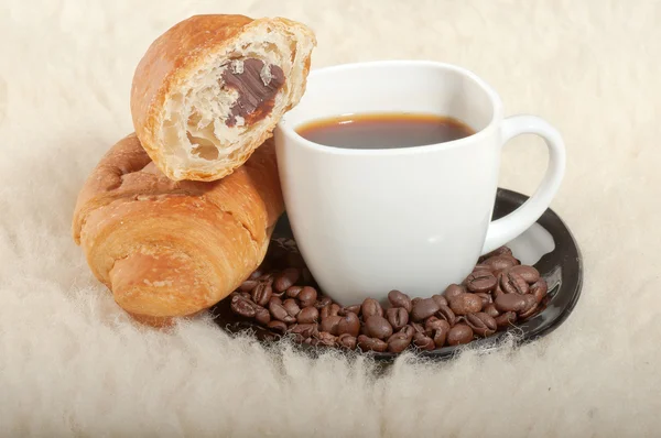 Croissant con café y frijoles sobre fondo de piel — Foto de Stock