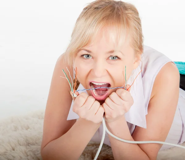 Beautiful crazy young woman biting network cable on warm plaid — Stock Photo, Image