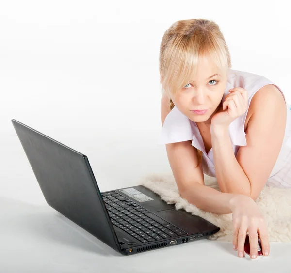 Beautiful young woman with a laptop lies on warm plaid — Stock Photo, Image