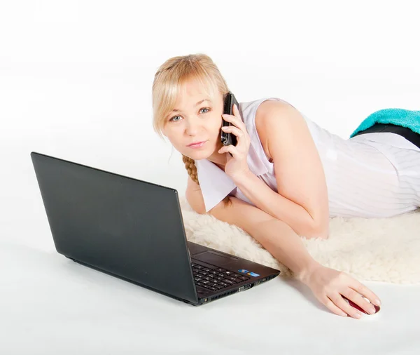 Mooie jonge vrouw met een laptop en de telefoon ligt op warme plaid — Stockfoto