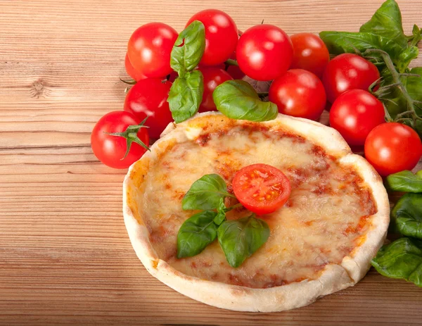 Close-up van pizza met tomaten, kaas en basilicum op houten achtergrond — Stockfoto