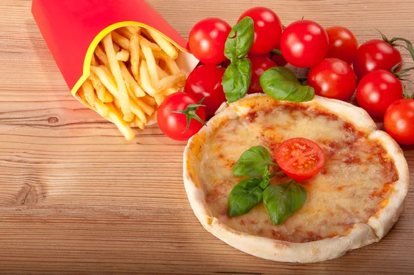Close-up van pizza withfrench frietjes, tomaten, kaas en basilicum op houten achtergrond — Stockfoto