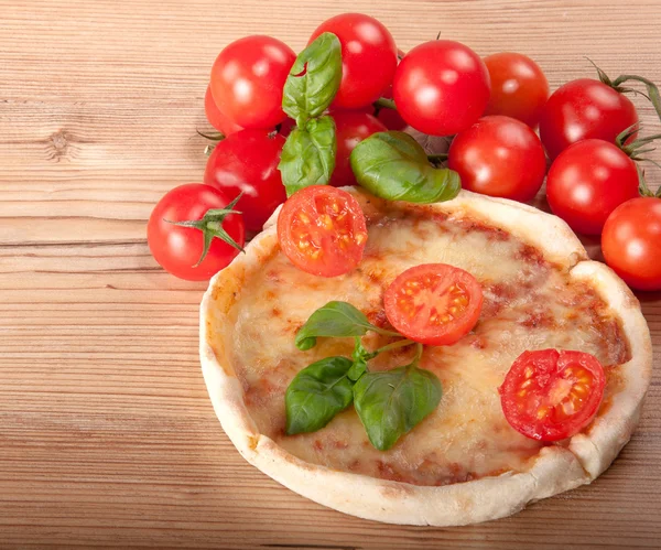 Close-up van pizza met tomaten, kaas en basilicum op houten achtergrond — Stockfoto