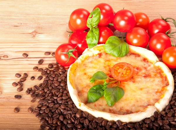 Close-up van pizza met koffie bonen, tomaten, kaas en basilicum op houten achtergrond — Stockfoto
