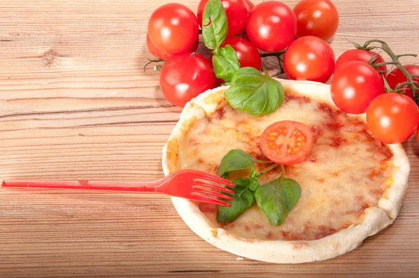 Close-up van pizza met rode vork, tomaten, kaas en basilicum op houten achtergrond — Stockfoto