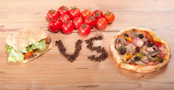 Tasty hamburger and pizza. vesrsus. vs. and some tomatoes Stock Photo