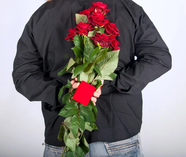 Imagina a un hombre sosteniendo una rosa roja y un joyero a sus espaldas. — Foto de Stock