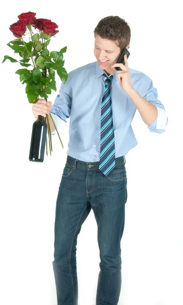 Jonge zakenman in blauwe overhemd en stropdas met fles wijn, bos van rode rozen spreken op een telefoon — Stockfoto