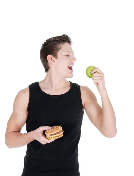 Retrato do homem escolhendo entre hambúrguer e maçã verde — Fotografia de Stock