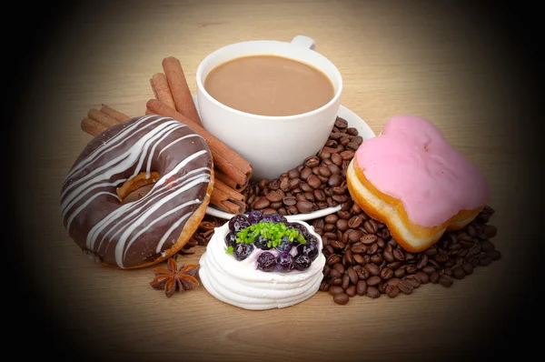 Taza de café, canela, anís en granos de café, pasteles dulces en el fondo — Foto de Stock