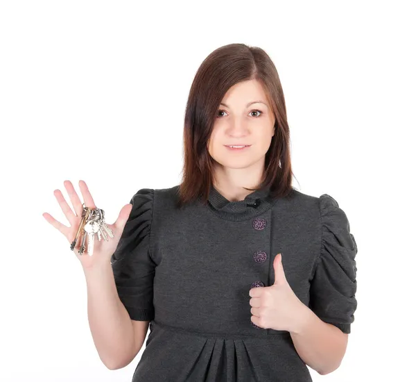 Unga vackra kvinnan visar lägenhet nycklar på vit bakgrund — Stockfoto