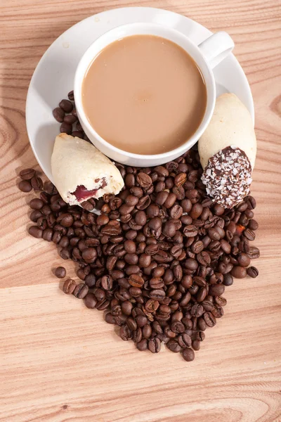 Кофейная чашка и кофейные зёрна, сладости на деревянном фоне — стоковое фото