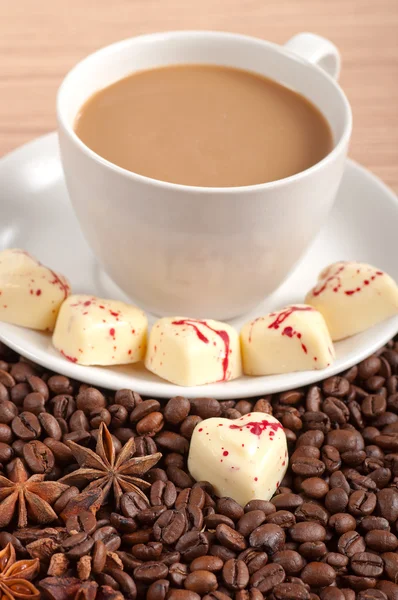 Taza de café con frijoles y chocolate blanco corazón caramelo sobre fondo de madera — Foto de Stock