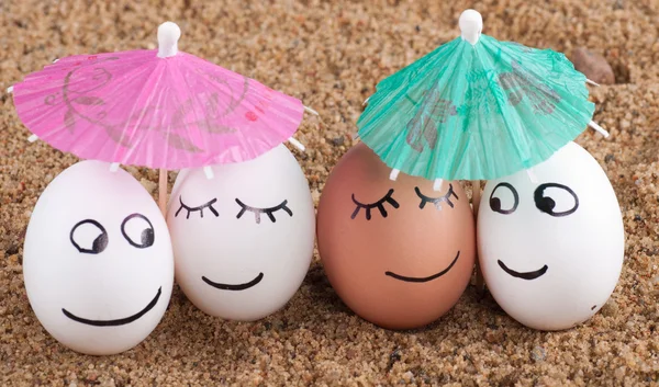 Vtipné velikonoční vajíčka pod deštníkem na písku — Stock fotografie