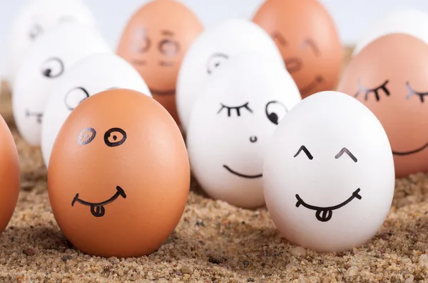 Group of Funny crazy smiling eggs on a sand — Stock Photo, Image