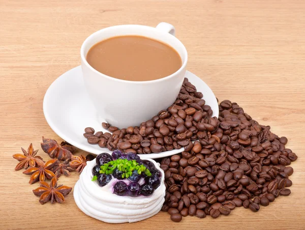 Coffee cup with coffee beans ans sweet cake on a wooden background — Stock Photo, Image