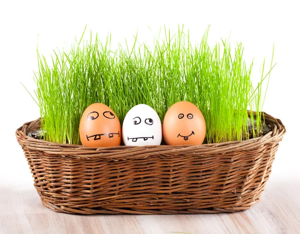 Three Funny crazy smiling eggs in basket with grass. sun bath. — Stock Photo, Image