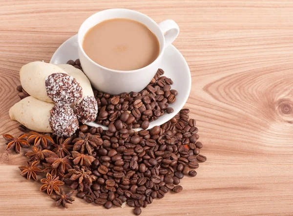 Φλιτζάνι καφέ, γλυκάνισο σε κόκκους καφέ, γλυκά στο ξύλινο πλαίσιο — Φωτογραφία Αρχείου