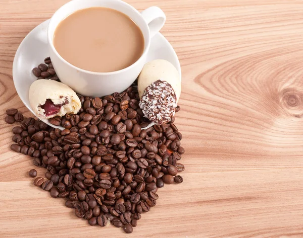 Coffee cup and coffee beans, sweets on the wooden background — Stock Photo, Image